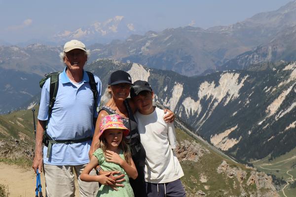 A family of four, including two adults and two children, poses for a photo on a mountain trail
